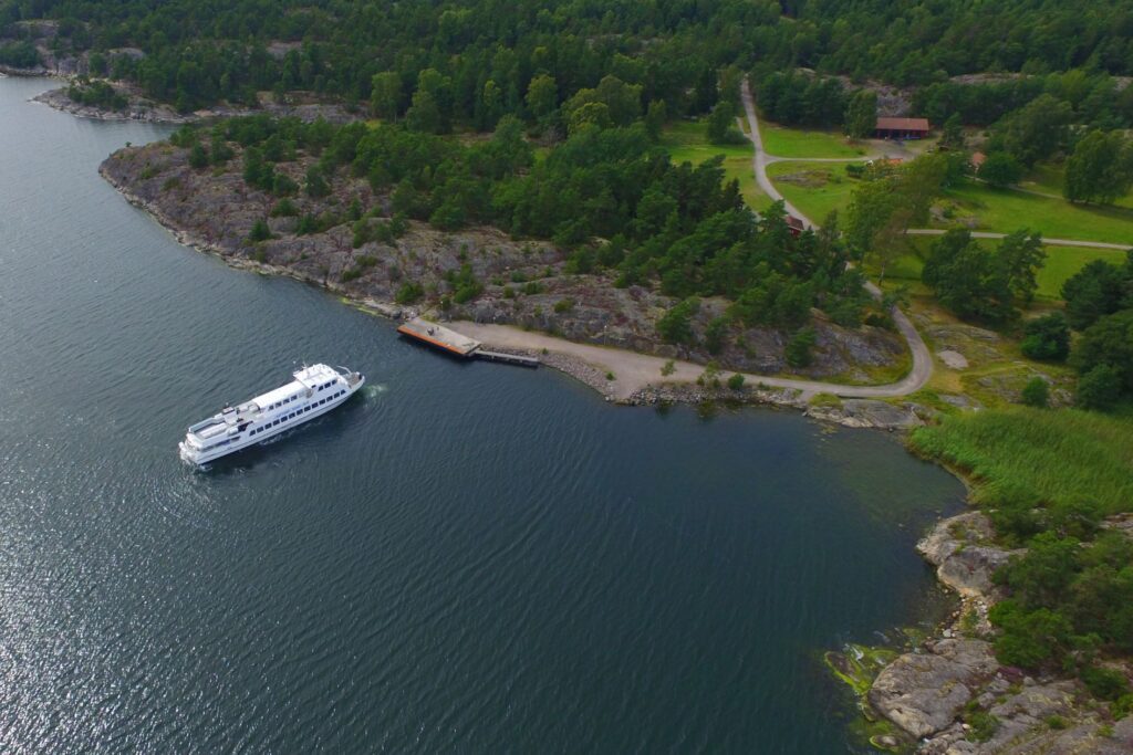 m/s Sjöbris operating a jetty in the archipelago, blue sea and green land.