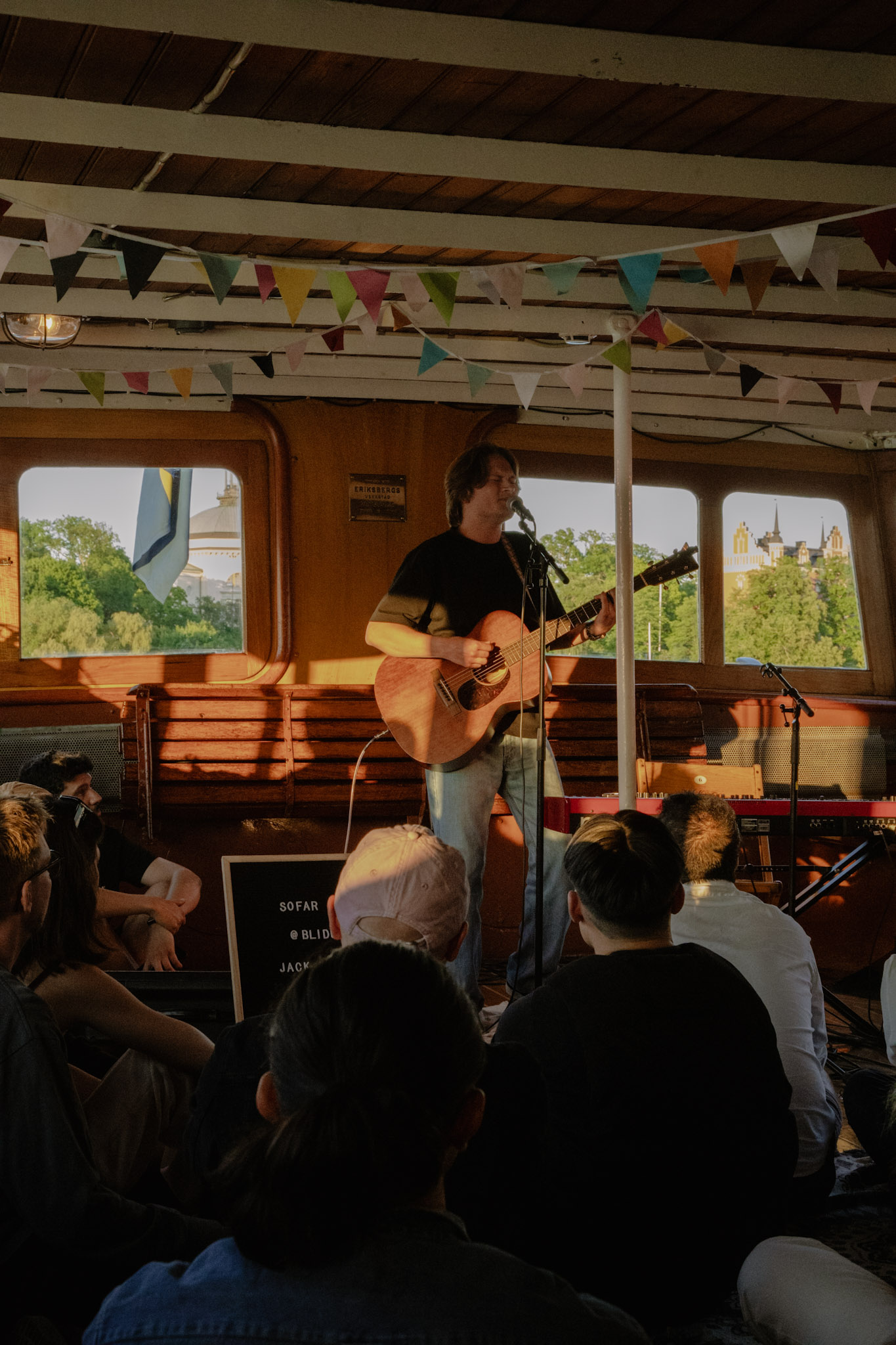 Small intimate music scene but with big experiences, a guy performing with guitar for a seated audience