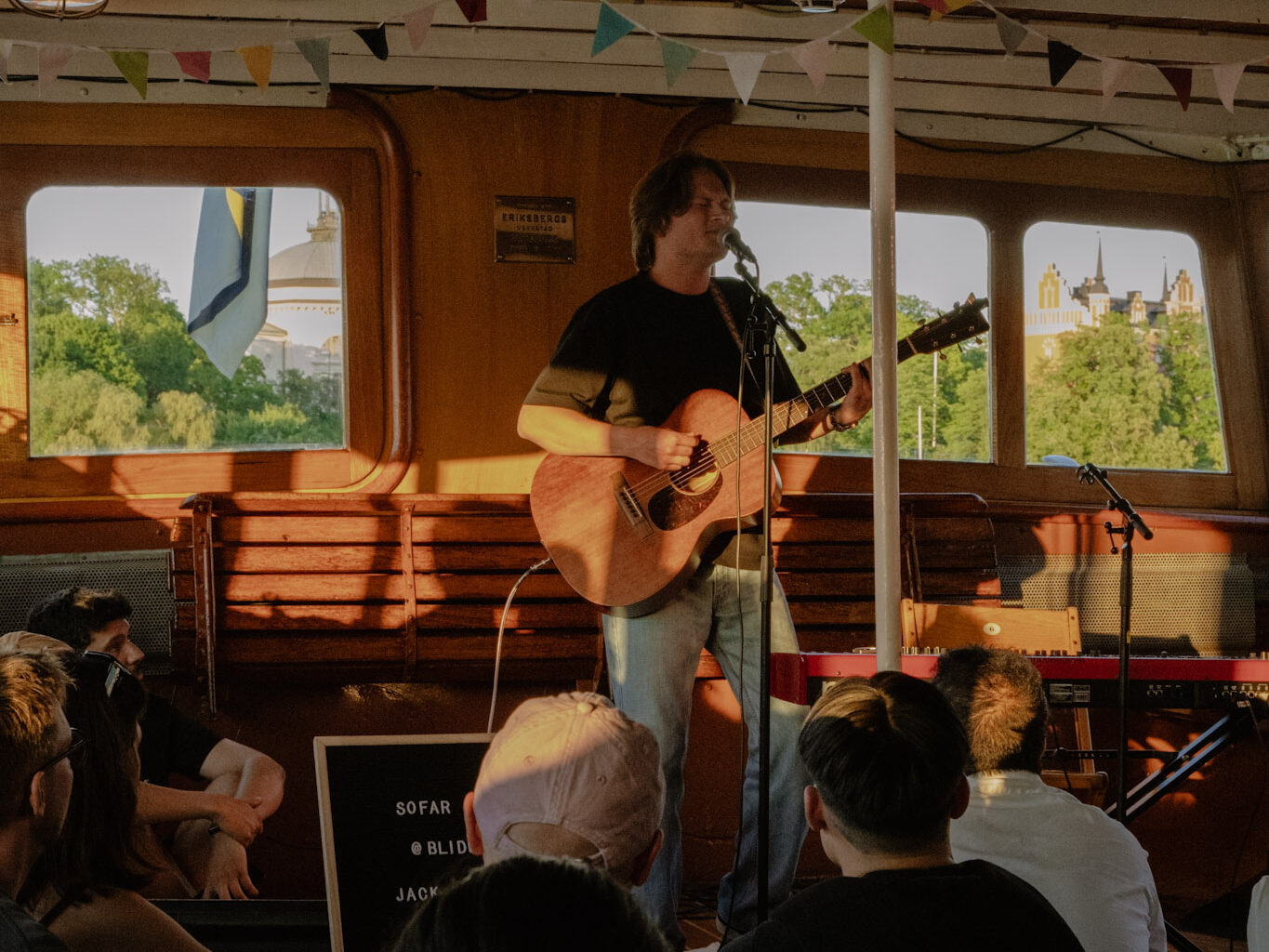 Small intimate music scene but with big experiences, a guy performing with guitar for a seated audience