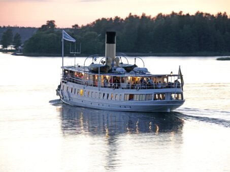 The steamship Blidösund sails in calm waters at sunset.