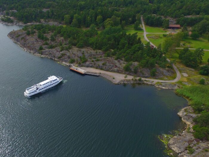 m/s Sjöbris operating a jetty in the archipelago, blue sea and green land.