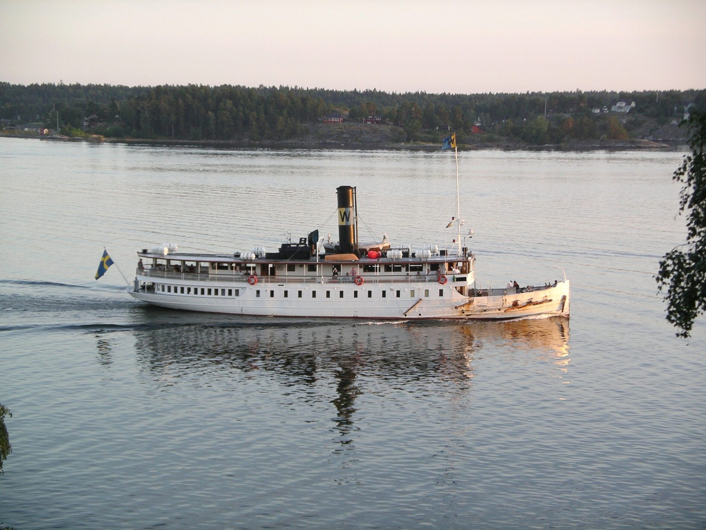 The classic steamship Storskär sails in mirror-like water